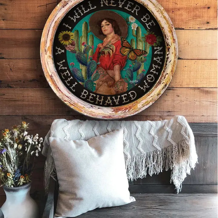 Western wall art with a woman and cacti design, text 'I will never be a well-behaved woman', on a wooden wall.