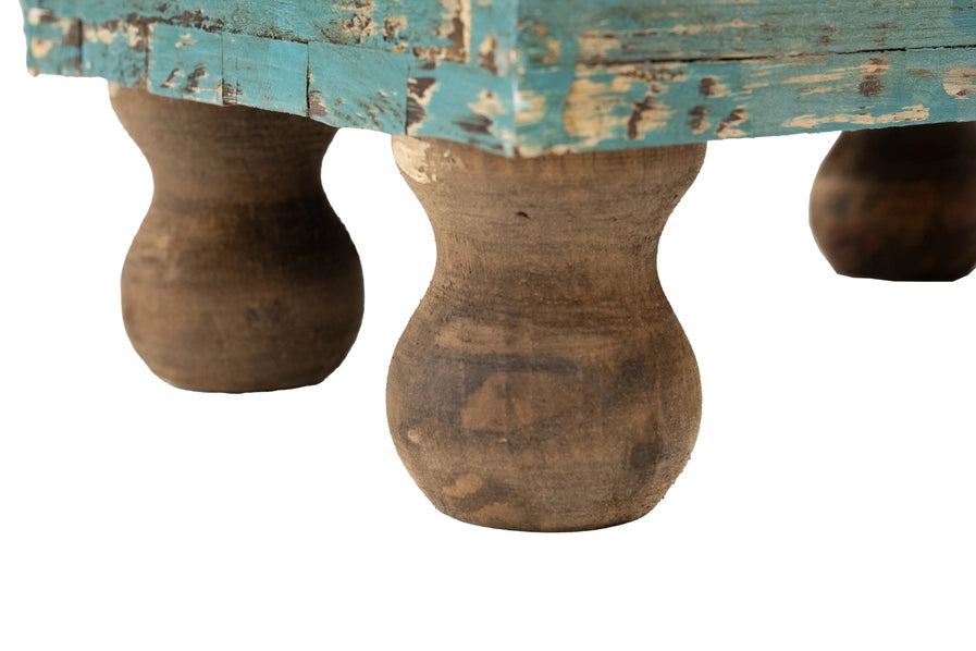 Close-up of a housewarming gift - wooden table with distressed blue top and round legs on a white background