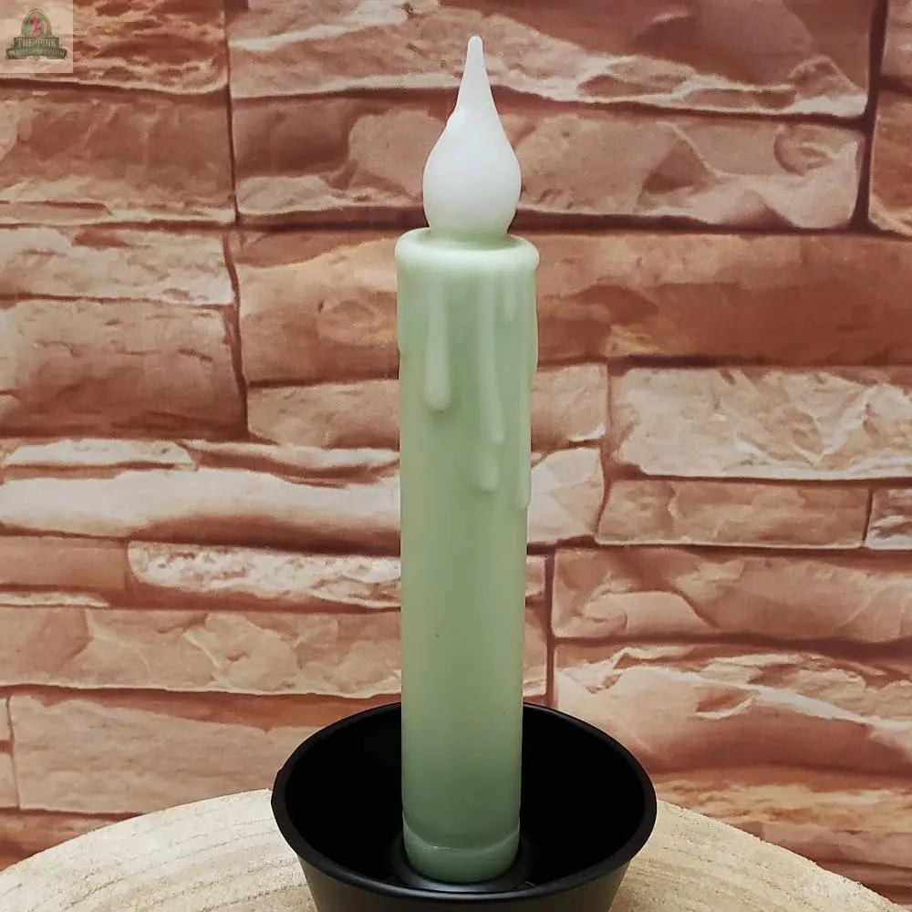 A 7" Timered Color Taper in black stands upright in a holder with melted wax drips, set against a textured brick-patterned background.