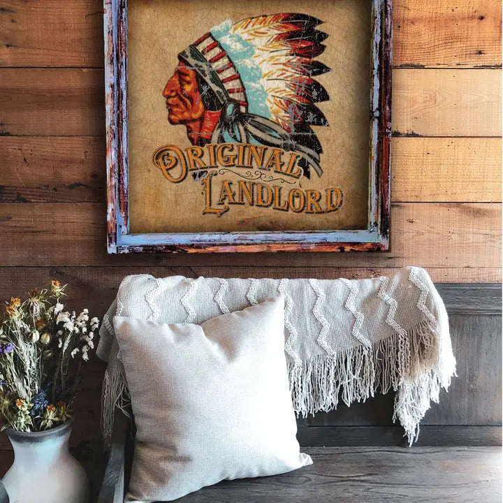 Decorative sign with Native American headdress design above a couch with pillows and a blanket.