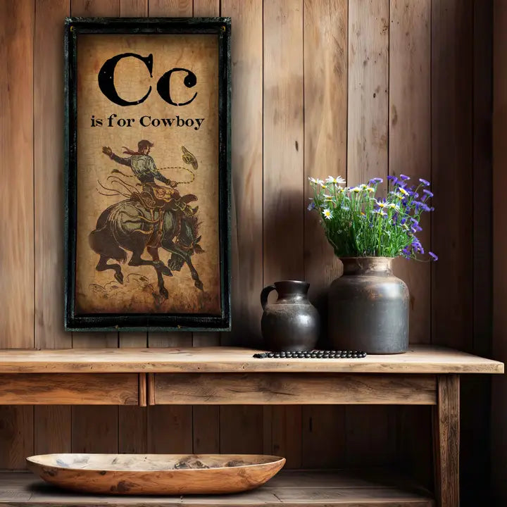 Western wall art with Cc is for Cowboy design, vases, and a bowl on a wooden shelf against a wooden wall.