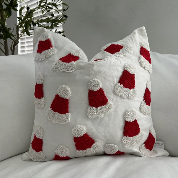 Decorative pillow with red and white Santa hat patterns on a neutral background