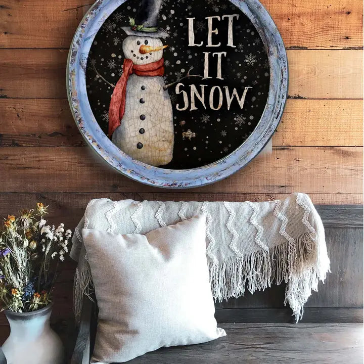 farmhouse wall decor with a snowman and 'Let It Snow' text on a wooden wall above a cozy seating area.