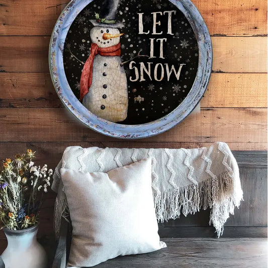 farmhouse wall decor with a snowman and 'Let It Snow' text on a wooden wall above a cozy seating area.