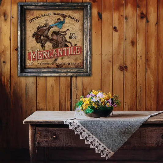 Vintage-style sign on a wooden wall above a rustic table with a floral arrangement.