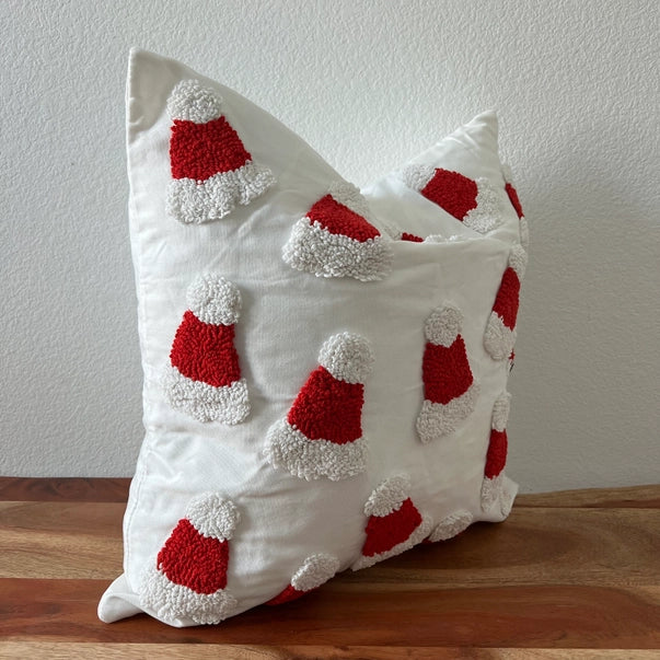 Decorative pillow with red and white santa hats on a wooden surface