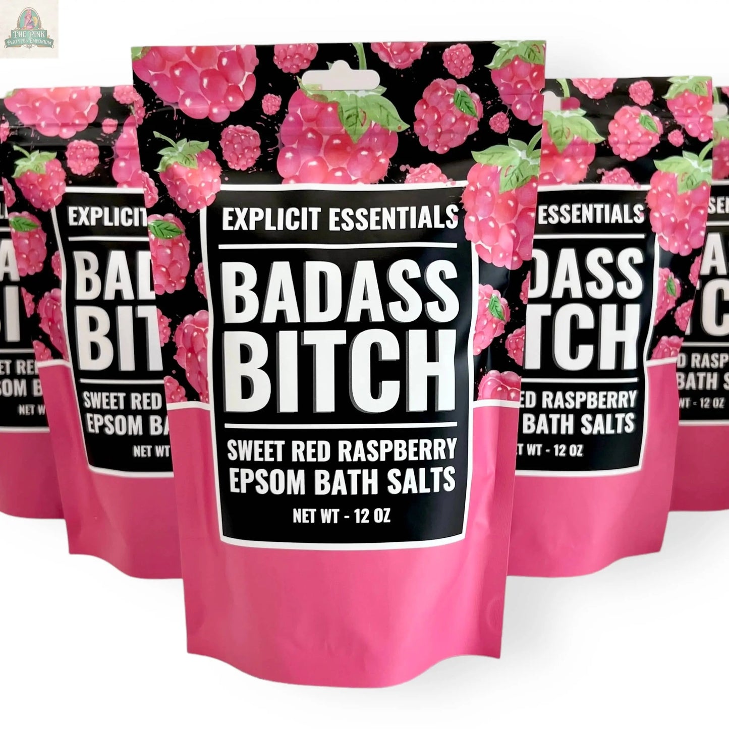 A 12oz stand-up pouch of Explicit Essentials' Bad Ass Bitch Bath Salts, featuring a black and pink raspberry-themed design, shown with similar products—a bold self-care gift.