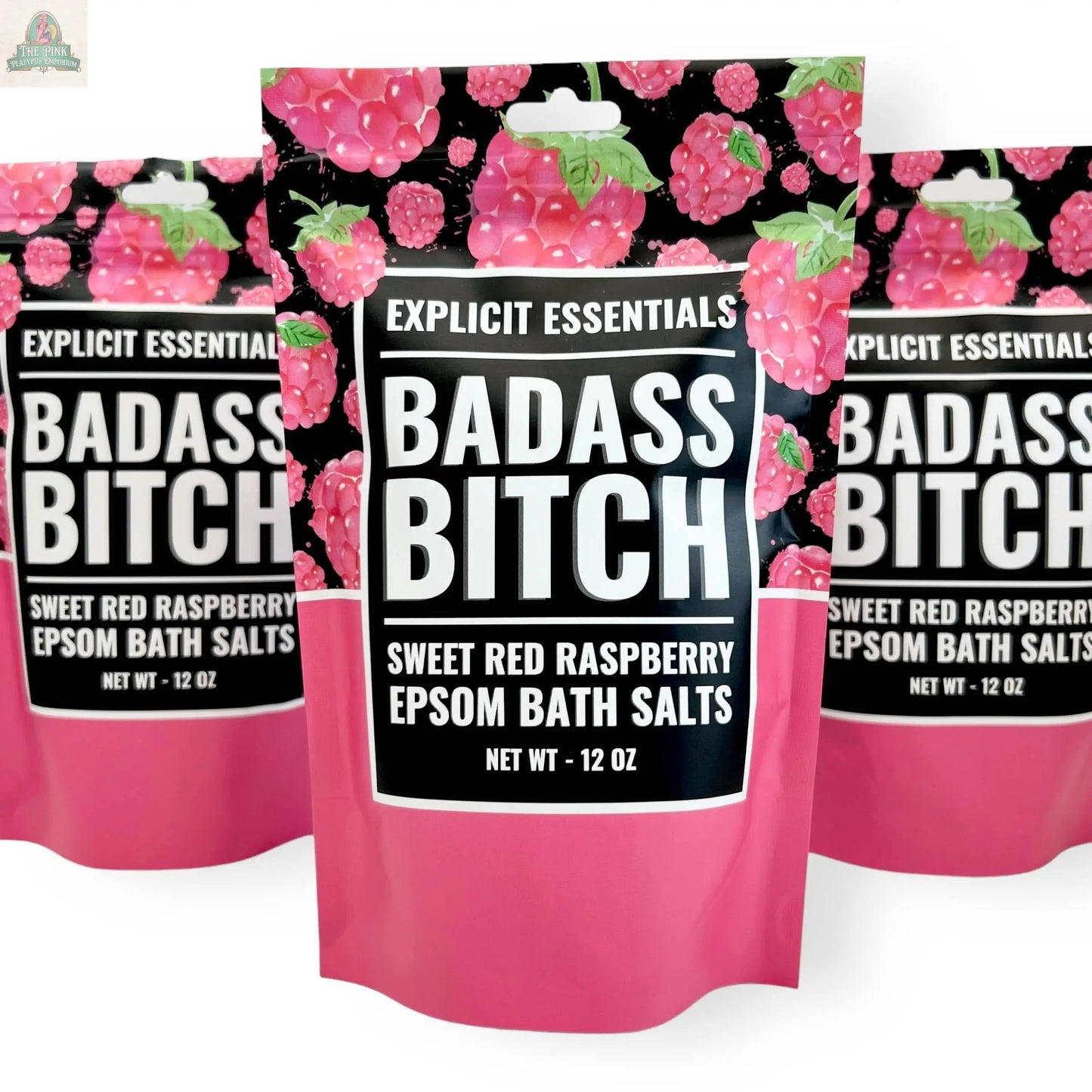 Three 12oz bags of Explicit Essentials' Bad Ass Bitch Bath Salts, featuring a pink and raspberry design, are displayed side by side—perfect for self-care or as a thoughtful gift.