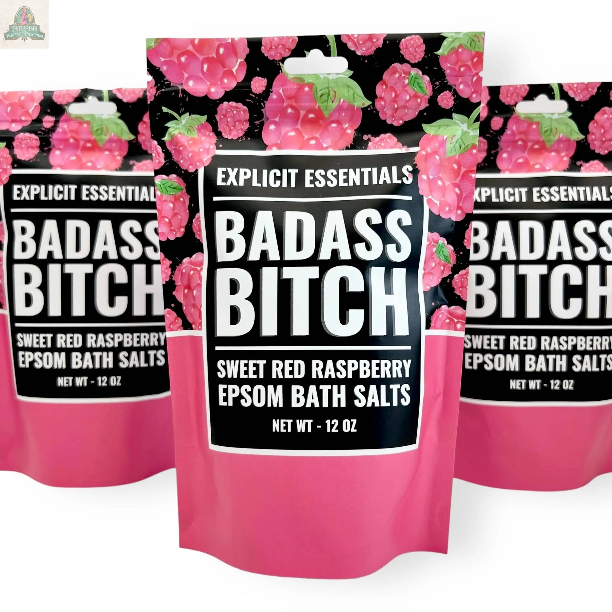 Three 12oz bags of Explicit Essentials' Bad Ass Bitch Bath Salts, featuring a pink and raspberry design, are displayed side by side—perfect for self-care or as a thoughtful gift.