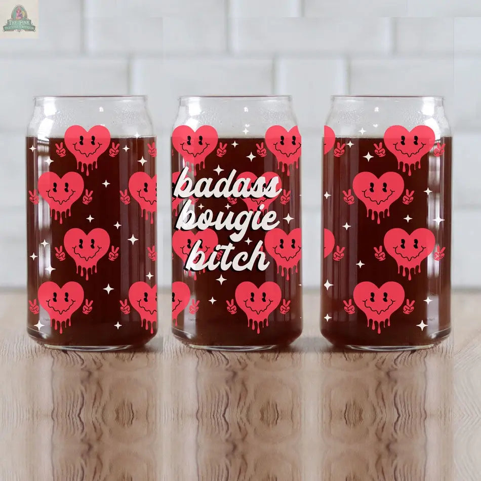 Three clear Badass Bougie 20oz glass cups with bamboo lids, filled with a dark drink and decorated with pink dripping hearts and white sparkles. The middle cup features a bold white script saying "Badass Bougie.