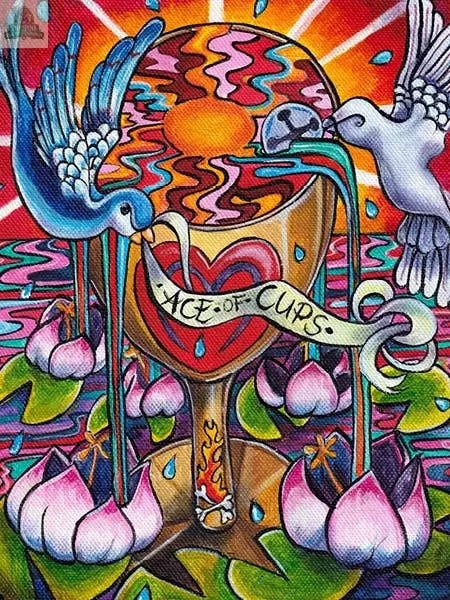 Colorful illustration from Bonefire Tarot, 2nd Edition by REDFeather: two birds pour water into a golden chalice labeled Ace of Cups, surrounded by lotus flowers, rippling water, and a radiant sun—evoking classic hand-painted Tarot art.