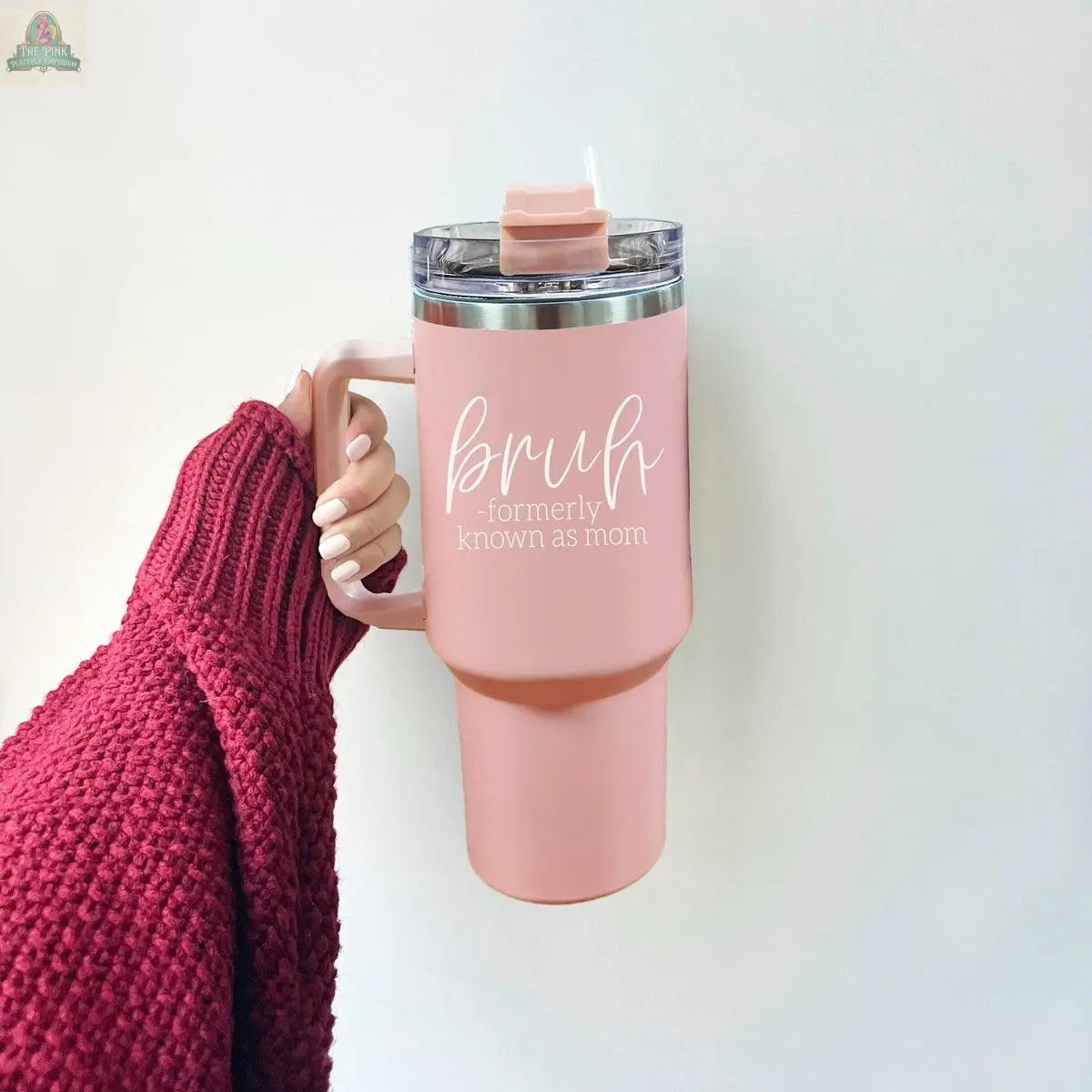 A hand in a maroon sweater holds the Bruh Pink 40oz tumbler with handle, featuring “bruh - formerly known as mom” in white script—perfect as a fun mom gift.