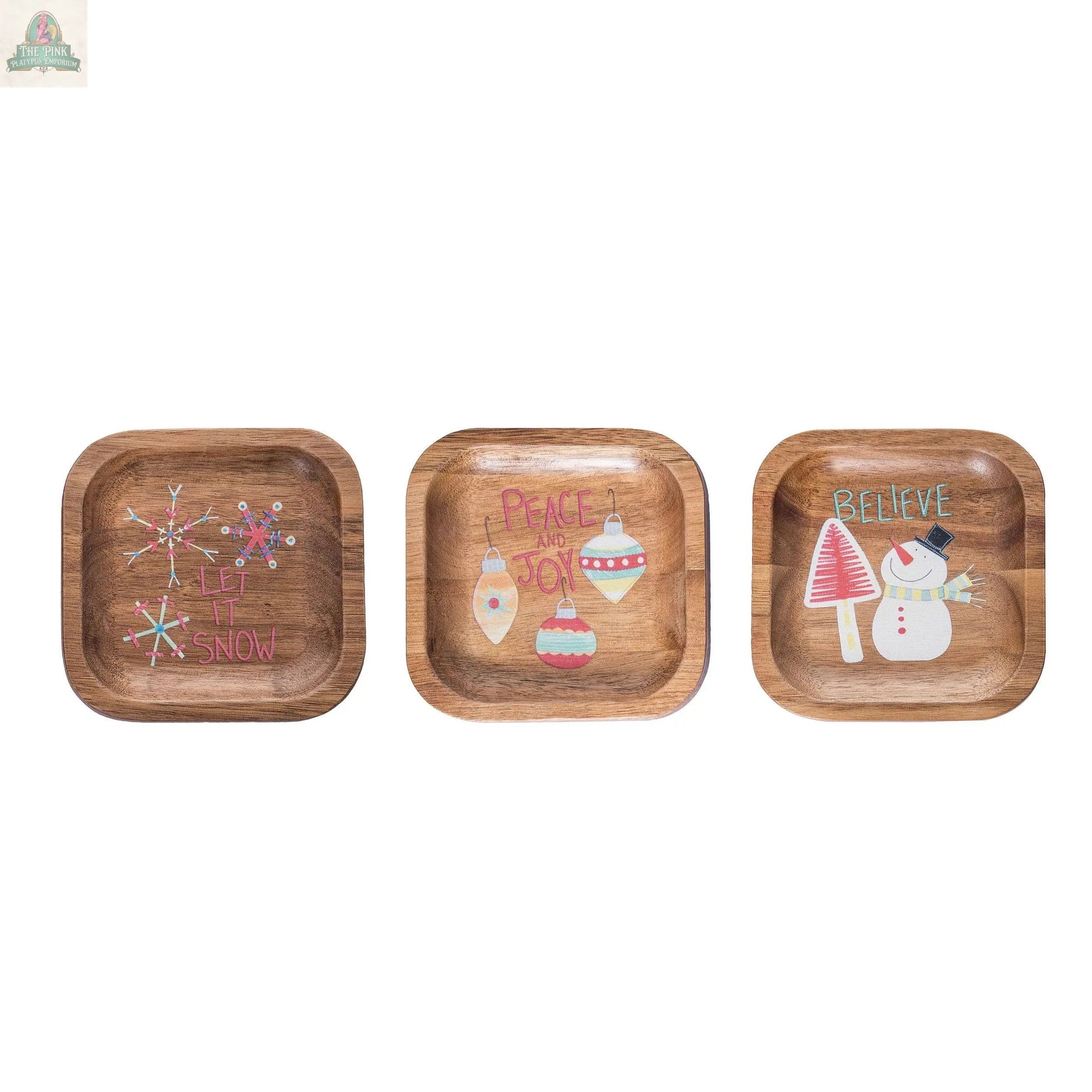 Decorative Wood Plates for Christmas: Set of 3 square dishes—one reads "Let it Snow" with pink snowflakes, another says "Peace and Joy" with ornaments, and the third features "Believe" with a snowman and red mushrooms. Perfect holiday decor!.
