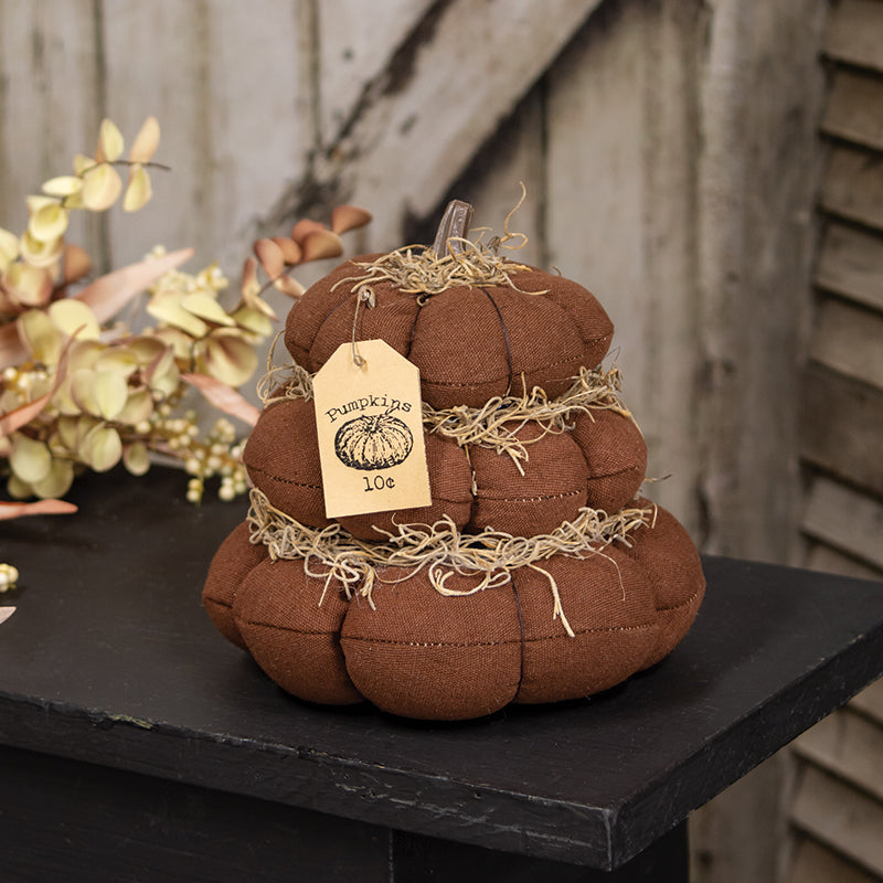 Fabric pumpkin decoration with a tag on a wooden surface