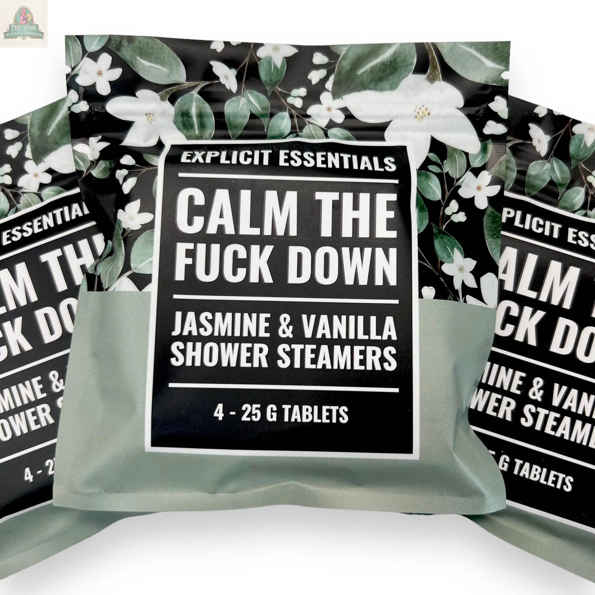 A box of Explicit Essentials Calm TF Down Shower Steamers, Jasmine & Vanilla scent (4 x 25g tabs) with a floral pattern, flanked by two partially visible identical aromatherapy shower steamer boxes.