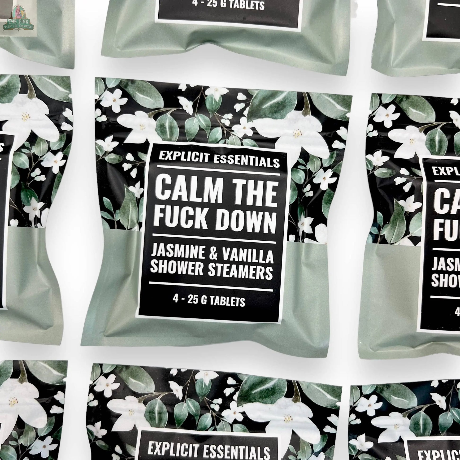 A package labeled Explicit Essentials Calm TF Down Shower Steamers, featuring floral designs, is shown among similar packages on a white background.