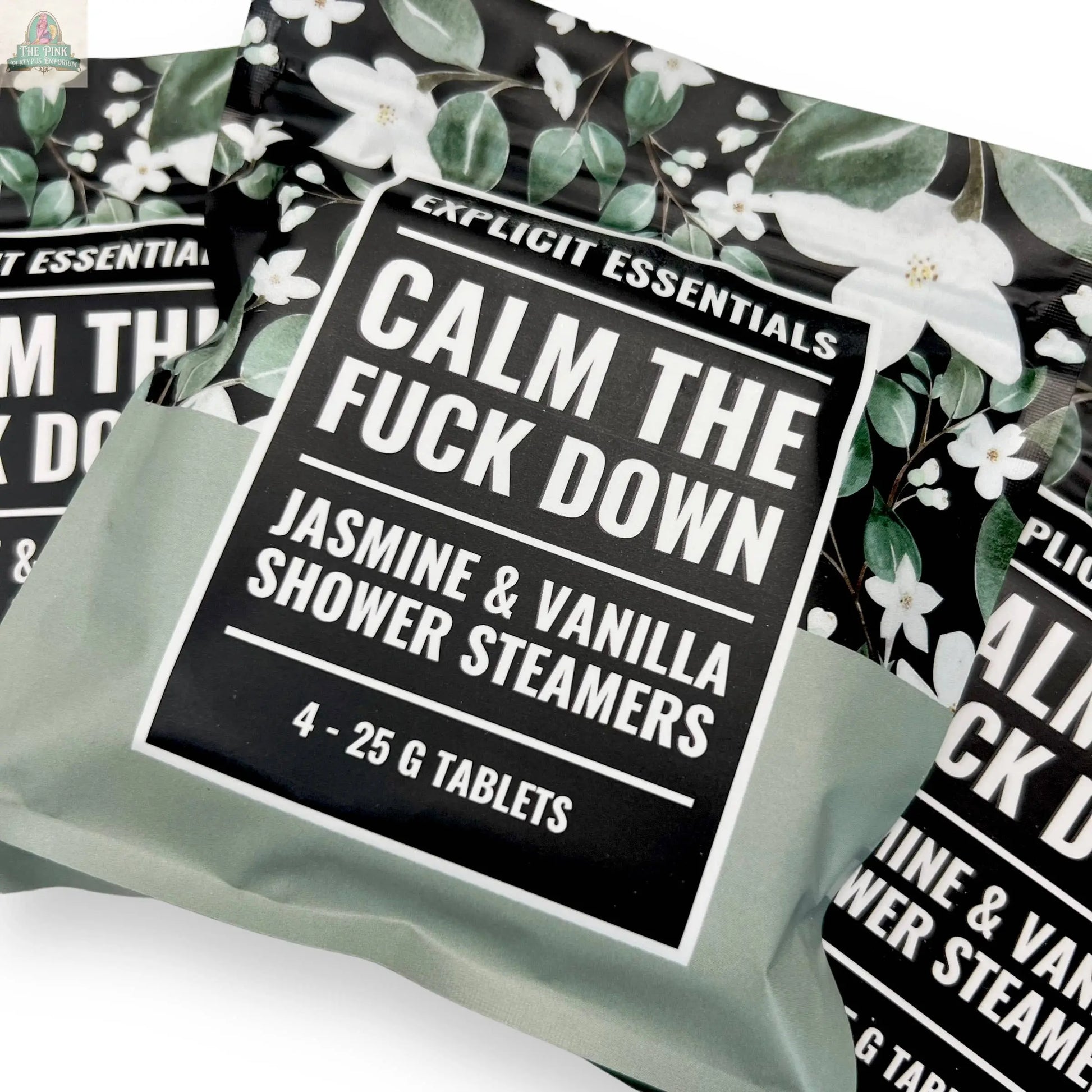 Explicit Essentials Calm TF Down Shower Steamers feature a jasmine & vanilla scent. Each pack includes four 25g tablets, packaged with white flowers and green leaves for an aromatherapy shower experience.