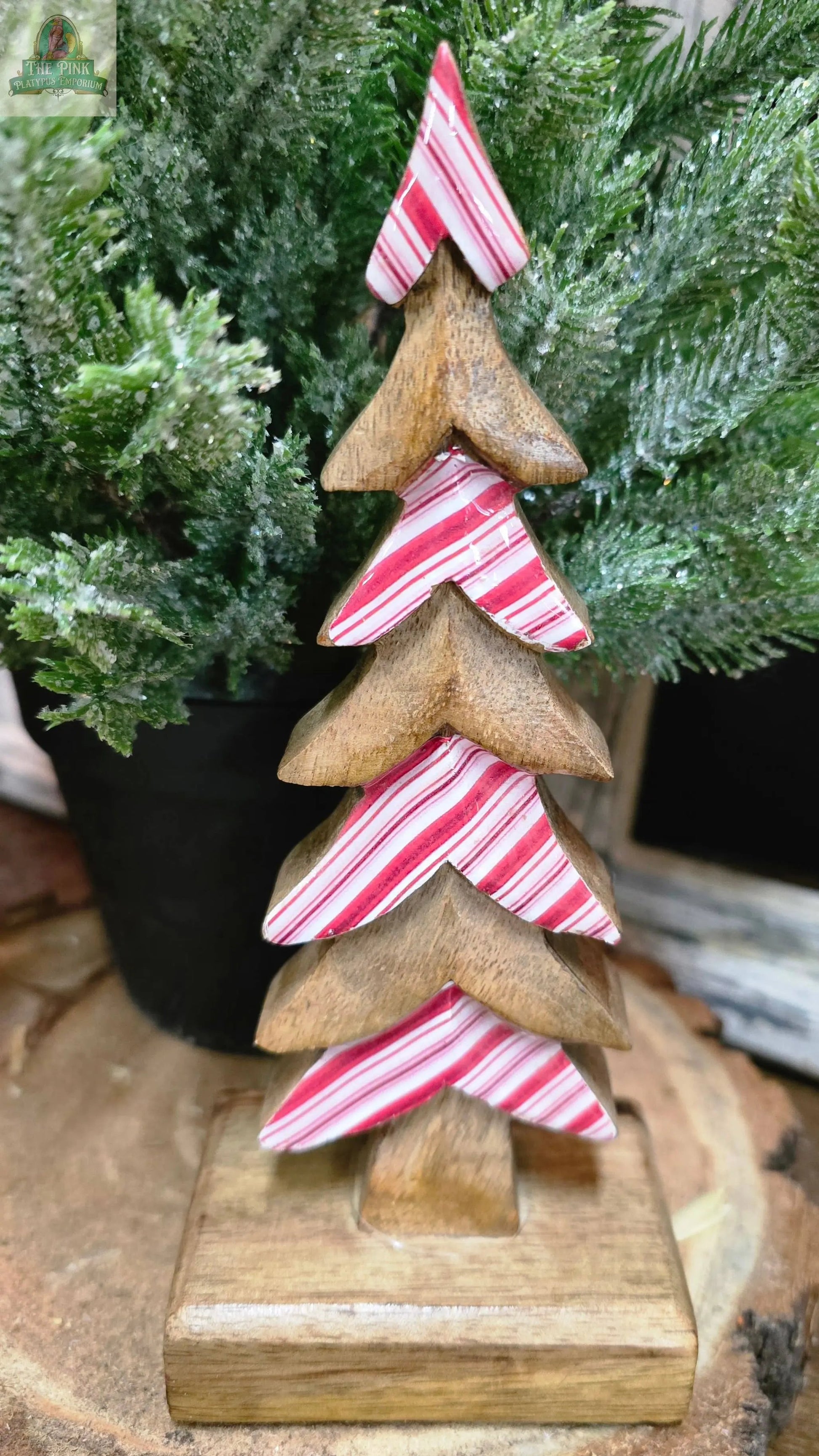 The Candy Striped Downswept 8x3.5x3in features alternating layers of natural wood and red-and-white stripes, creating a charming decorative Christmas tree for your holiday tabletop décor.