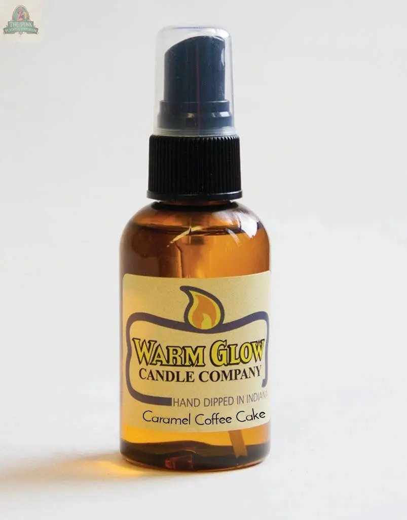 A small amber spray bottle labeled Caramel Coffee Cake Atomizer Oils with a black spray top sits against a plain background—ideal for enhancing any space without electric candles or potpourri.
