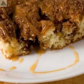 A bottle of Caramel Coffee Cake Atomizer Oils, capturing the scent of crumbly cake and golden caramel, rests on a white plate beside softly glowing electric candles.