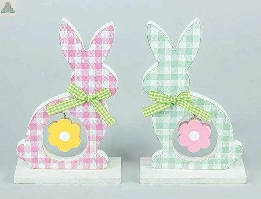 The Checkered Cottontail with Flower Tabletop 2 Assorted features one pink and one green bunny figurine with bows and flower cutouts, standing on white bases. Ideal for spring décor or farmhouse Easter decorations.