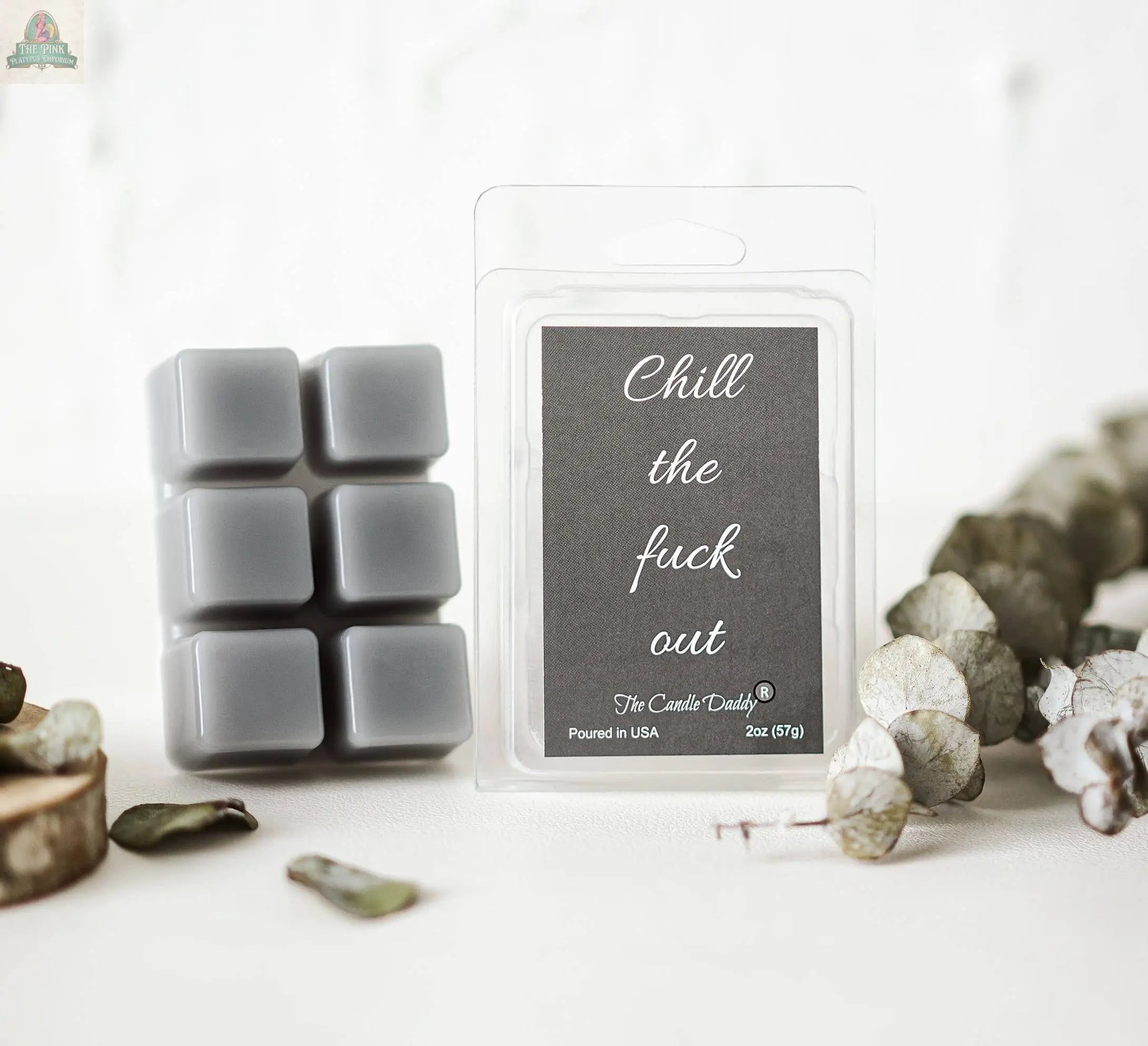 A pack of Chill the Fuck Out - Eucalyptus Mint Scented Wax Melts sits beside its packaging, which says "Chill the fuck out" in white script on a black label, with dried eucalyptus leaves and wooden slices nearby.
