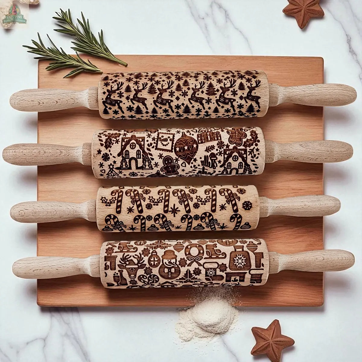 The Christmas Rolling Pin Set | 10 Styles features engraved festive designs. Shown on a wooden board with star cookies, rosemary, and flour—these holiday pins make the perfect gift for bakers this season.