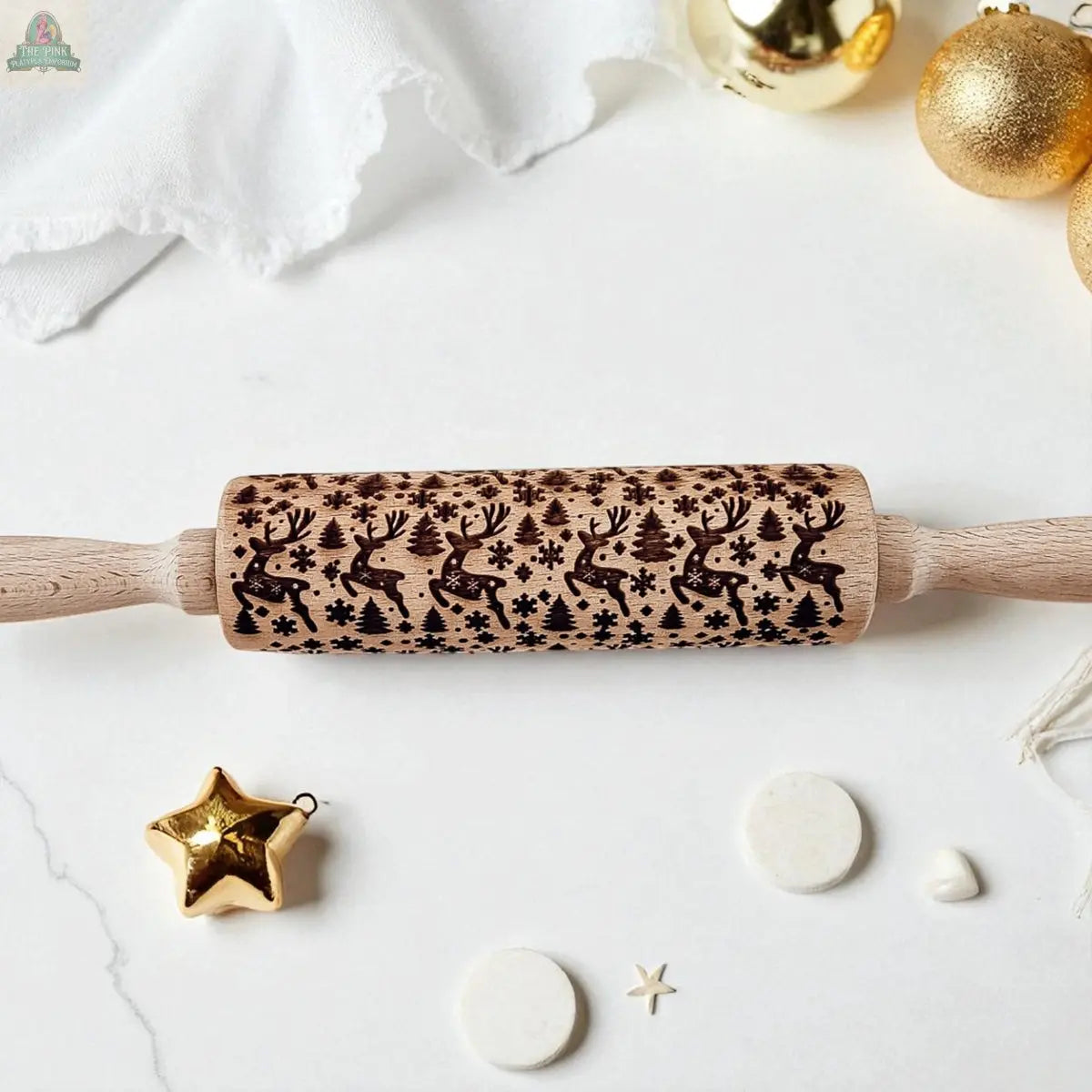 The Christmas Rolling Pin Set | 10 Styles features engraved holiday patterns, perfect for festive baking, and is shown on a white surface with gold ornaments, a star decoration, and white fabric nearby.