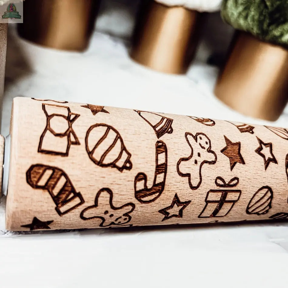 The Christmas Rolling Pin Set | 10 Styles features festive engravings like candy canes, gingerbread men, ornaments, stars, and presents—perfect for bakers or pairing with cookie cutters. Blurred Christmas trees add a holiday touch.