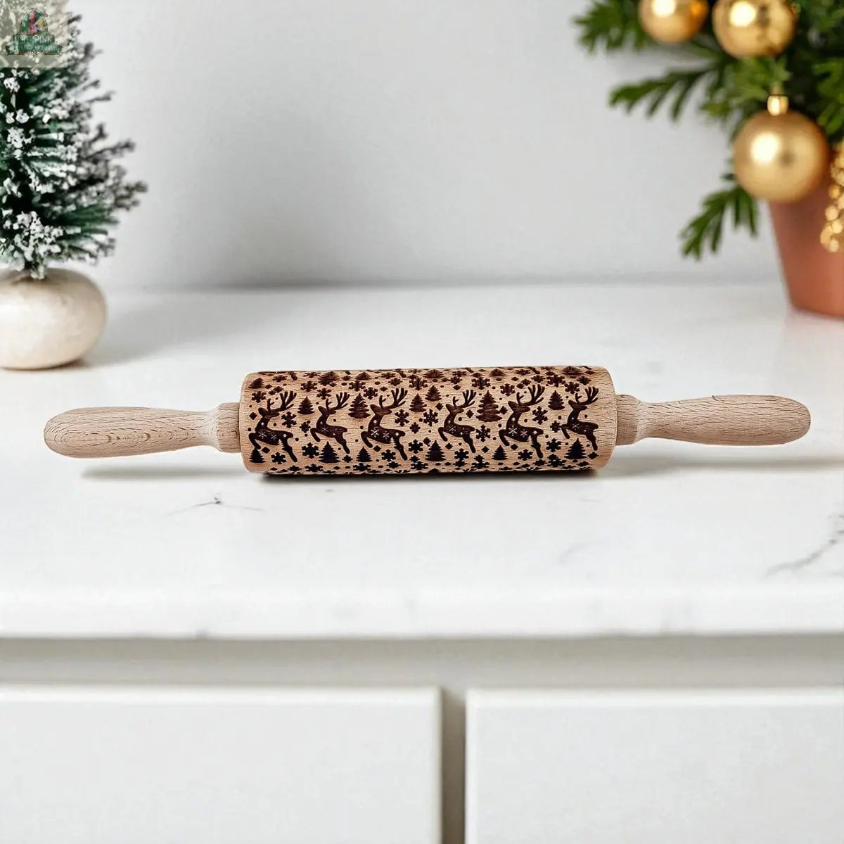 The Christmas Rolling Pin Set | 10 Styles features festive designs like reindeer and snowflakes, shown on a white countertop with small Christmas trees and cookie cutters—an ideal, thoughtful baking gift for the holidays.