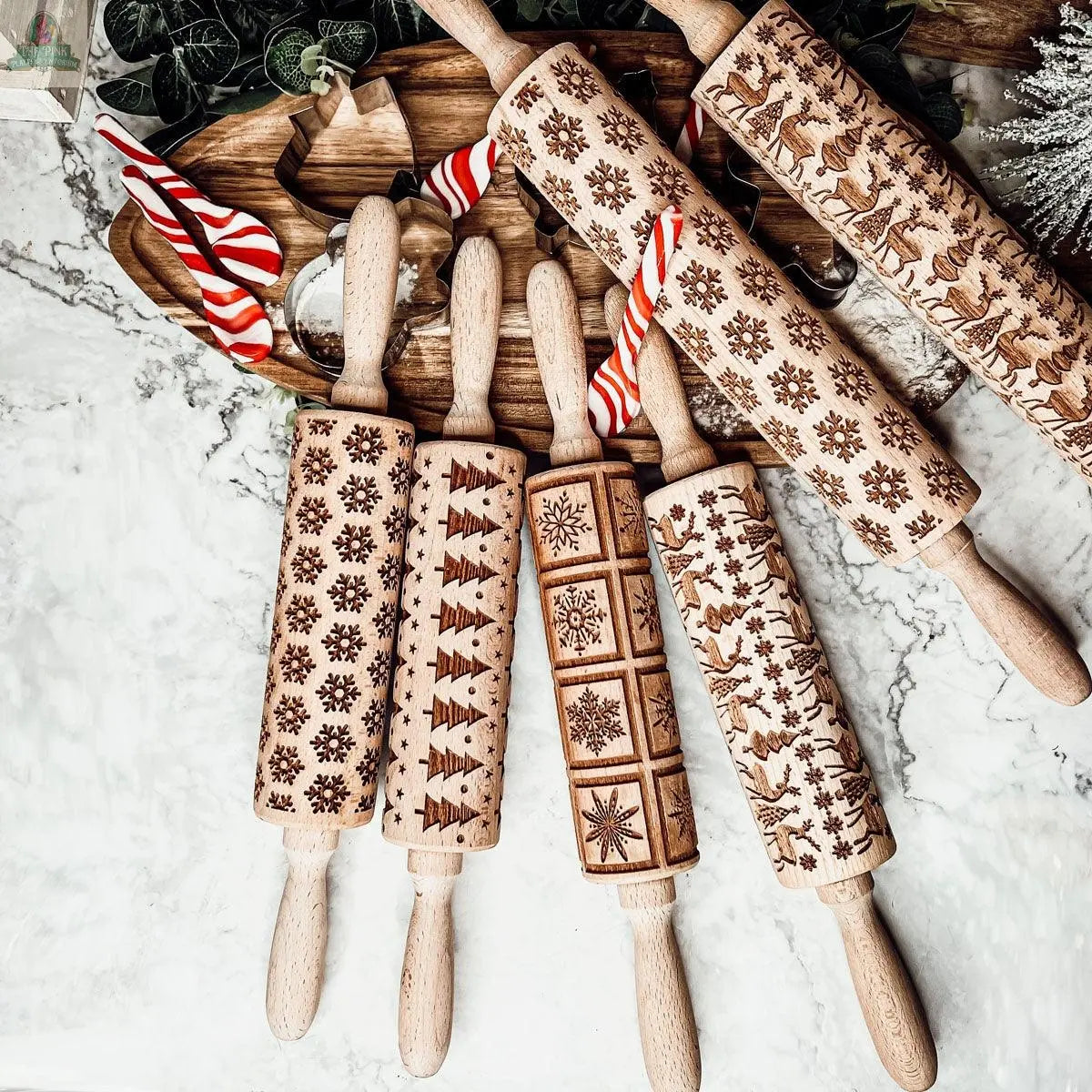 The Christmas Rolling Pin Set | 10 Styles includes engraved festive rolling pins, perfect for holiday baking and pairing with your favorite cookie cutters—arranged with candy canes and greenery for a festive touch.