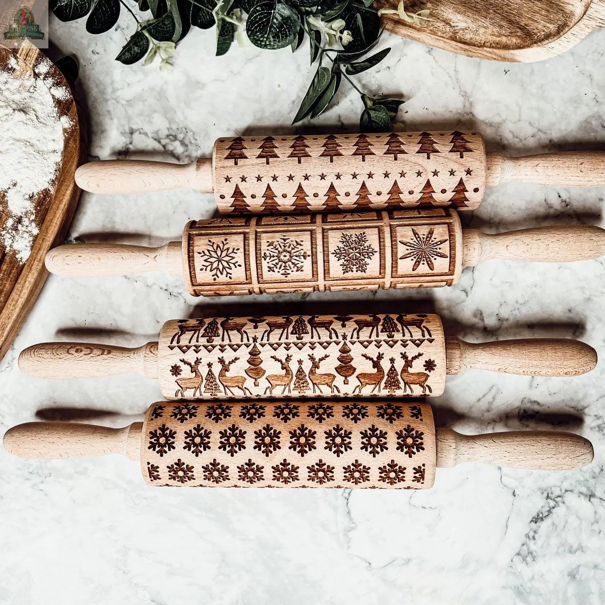 The Christmas Rolling Pin Set | 10 Styles features engraved pins with patterns like trees, snowflakes, and ornaments, arranged on a marble counter with baking items—an ideal festive gift for bakers.