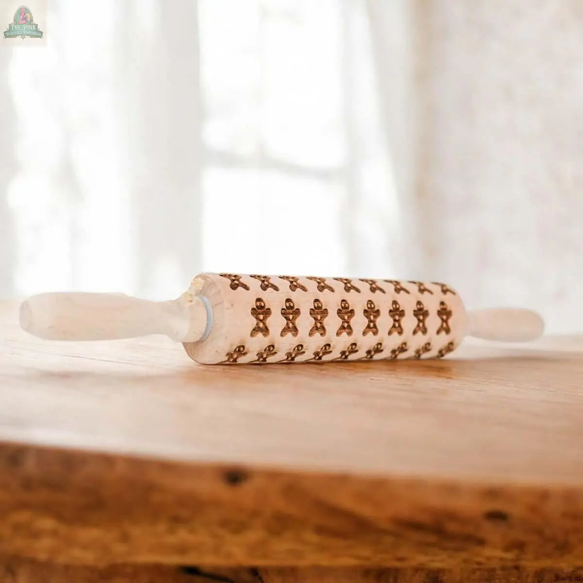 The Christmas Rolling Pin Set | 10 Styles features engraved gingerbread man patterns, resting on a wooden table with soft natural light, making it a charming baking gift.