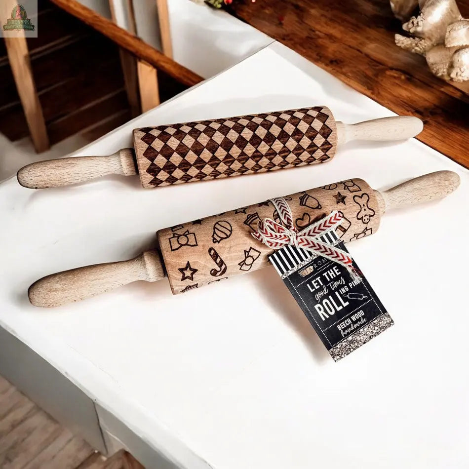 Two wooden rolling pins from the Christmas Rolling Pin Set | 10 Styles rest on a white surface—one with a checkered design, the other with baking-themed icons—ideal for holiday baking and pairing with your favorite cookie cutters.