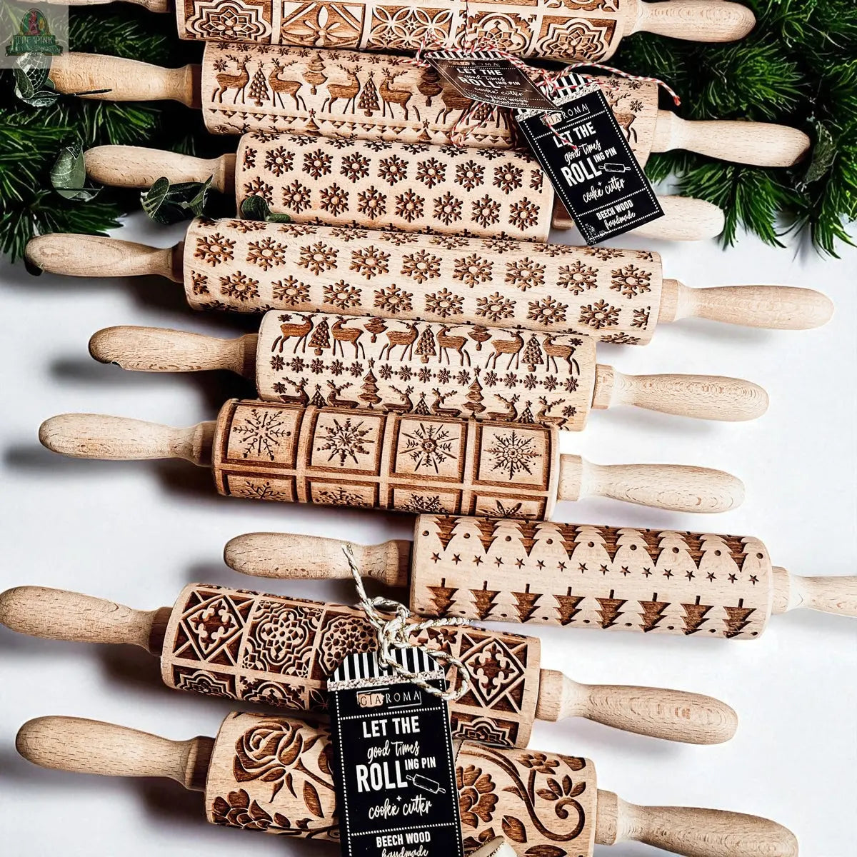 The Christmas Rolling Pin Set | 10 Styles features engraved wooden pins with festive patterns—snowflakes, reindeer, and more—displayed with green foliage and gift tags, making a unique baking gift for any kitchen enthusiast.