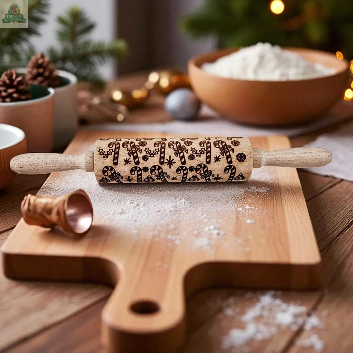 The Christmas Rolling Pin Set | 10 Styles rests on a floured wooden board, amid cookie cutters, baking ingredients, pinecones, and a Christmas tree for festive holiday baking.