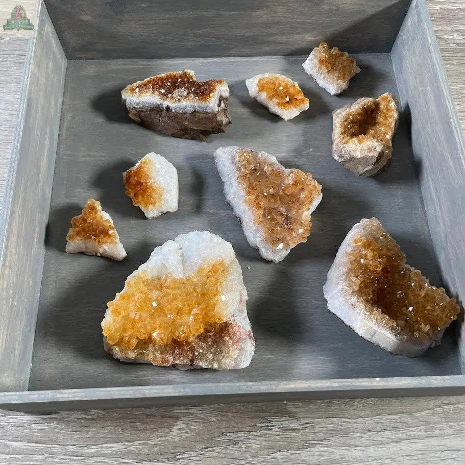 The Citrine Crystal Cluster – Natural Golden Gemstone Décor by Keystone Crystals from Pink Platypus Emporium adds vibrant yellow and orange hues to your décor, beautifully displayed on a gray tray atop a light wooden surface.