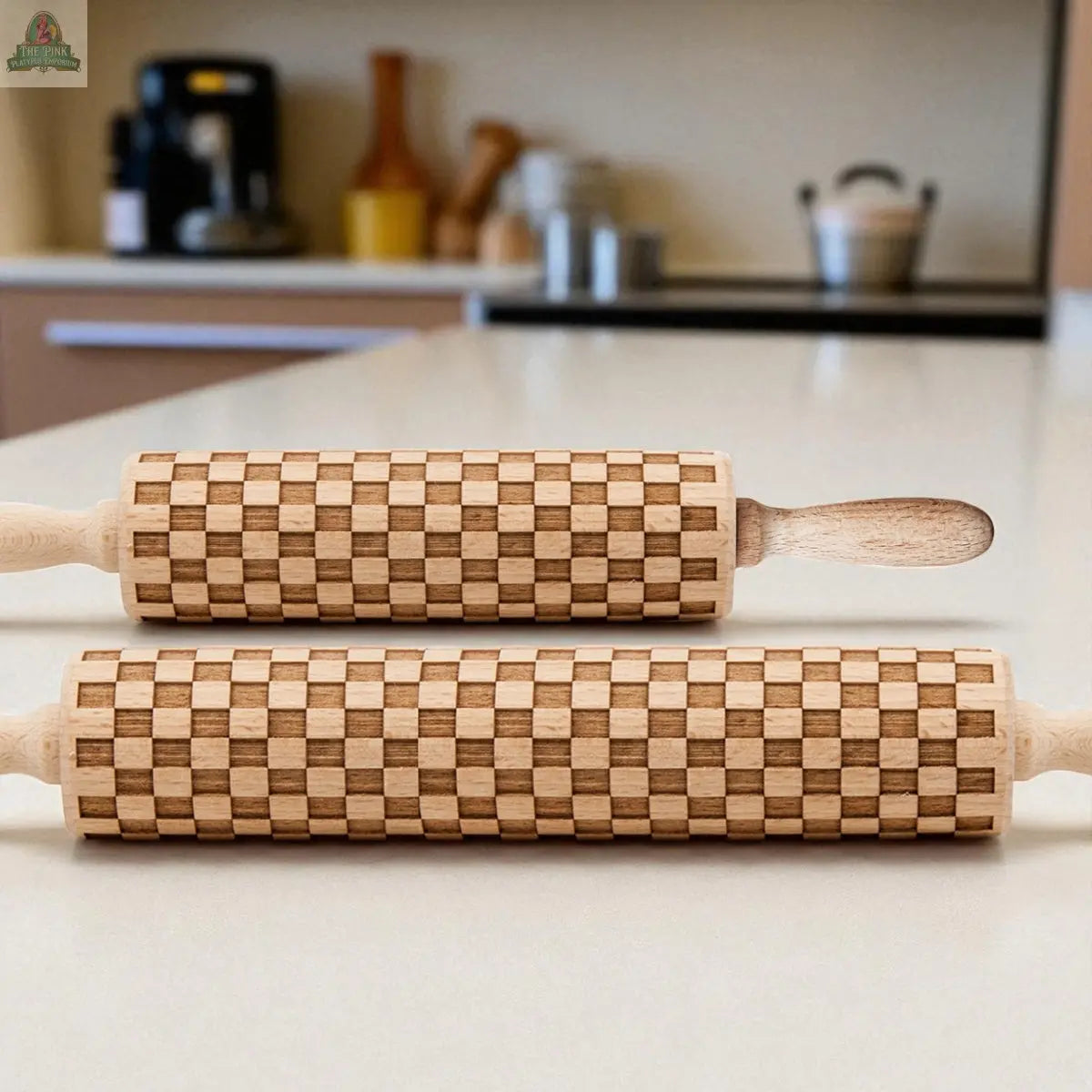 Two Courtly Check rolling pins lie parallel on a white kitchen countertop with a modern kitchen in the background—stylish and functional baking tools perfect for your kitchen.