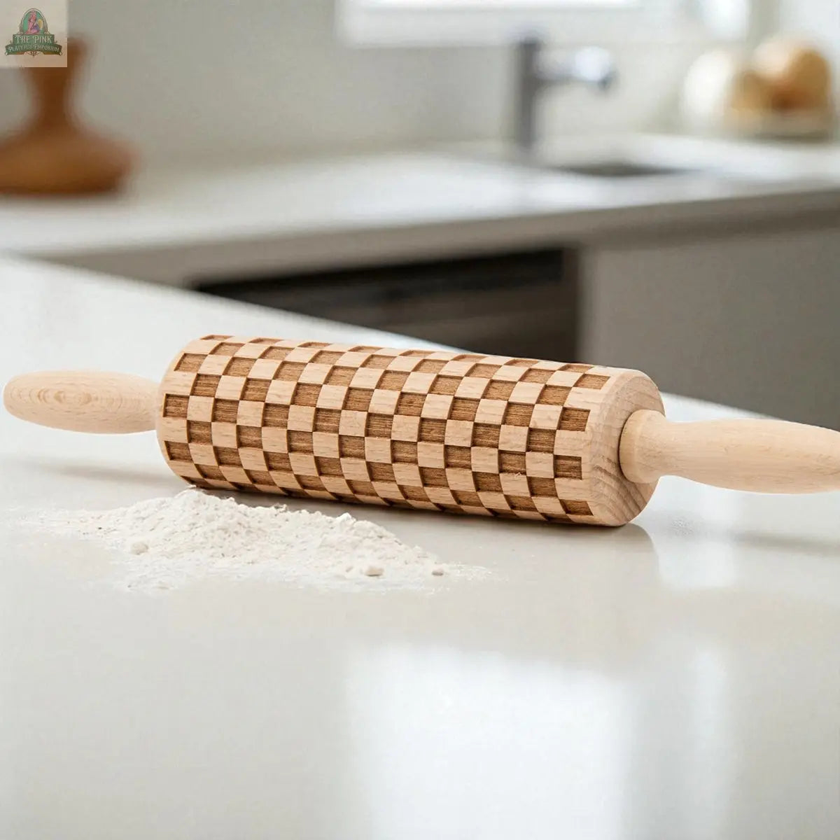 A Courtly Check rolling pin sits on a white countertop in a modern kitchen, surrounded by flour, cookie cutters, and baking tools.