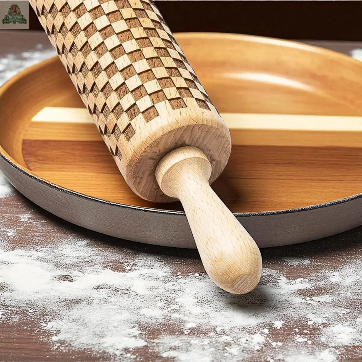 The Courtly Check Rolling Pin, featuring a classic checkerboard design, rests on a wooden plate dusted with flour—a stylish essential for bakers—displayed on a dark surface.