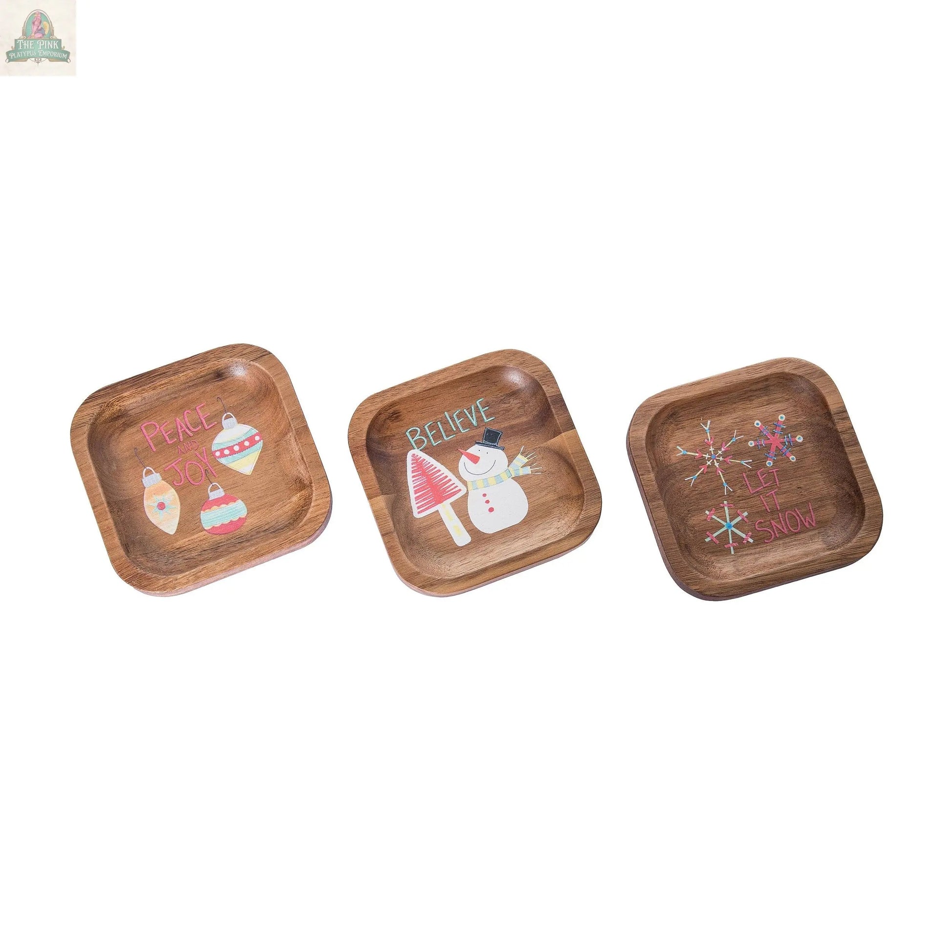 Decorative Wood Plates for Christmas feature three square wood dishes with festive designs—ornaments with PEACE & JOY, mushrooms and a snowman with BELIEVE, and snowflakes with LET IT SNOW—perfect for holiday decor.