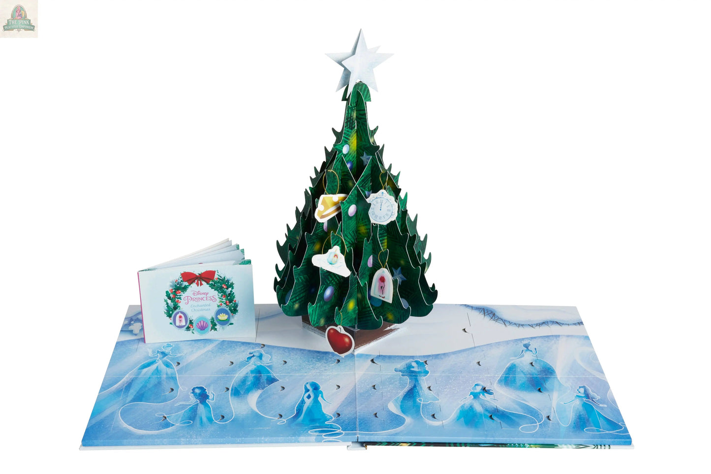 The Disney Princess: Enchanted Christmas Advent Calendar is a pop-up book with a 3D Christmas Tree decorated with collectible ornaments, blue angel illustrations on snowy pages, and a small closed booklet beside it.