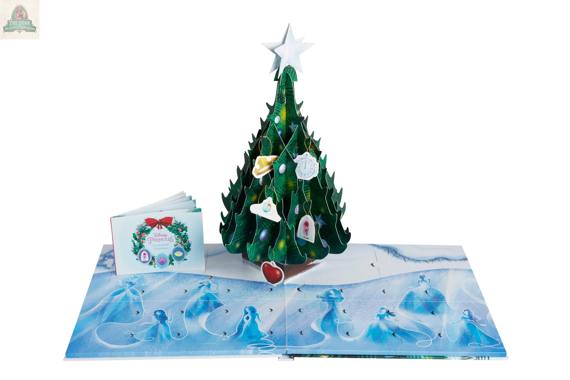 The Disney Princess: Enchanted Christmas Advent Calendar is a pop-up book with a 3D Christmas Tree decorated with collectible ornaments, blue angel illustrations on snowy pages, and a small closed booklet beside it.