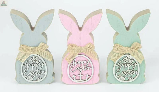 The Easter Egg Cutout Bunny Tabletop 3 Ast includes blue, pink, and green wooden bunnies (3.15x6.5x0.98 in) with bows, "Happy Easter" signs, and unique Easter-themed cutout accents on their backs.