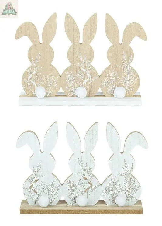 The Floral Bunny Trio Tabletop 2 Ast includes two sets of wooden bunny trios (11.5x1.97x8.27 in): one natural wood with white tails, the other white with wood bases and floral patterns—perfect for decorative displays.
