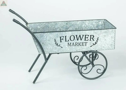 The Flower Market Wheel Barrow features a galvanized finish, ornate black metal handles, "Flower Market" printed on the side, and a solid tire styled like a 15x6x10 forklift tire for a unique, decorative look.