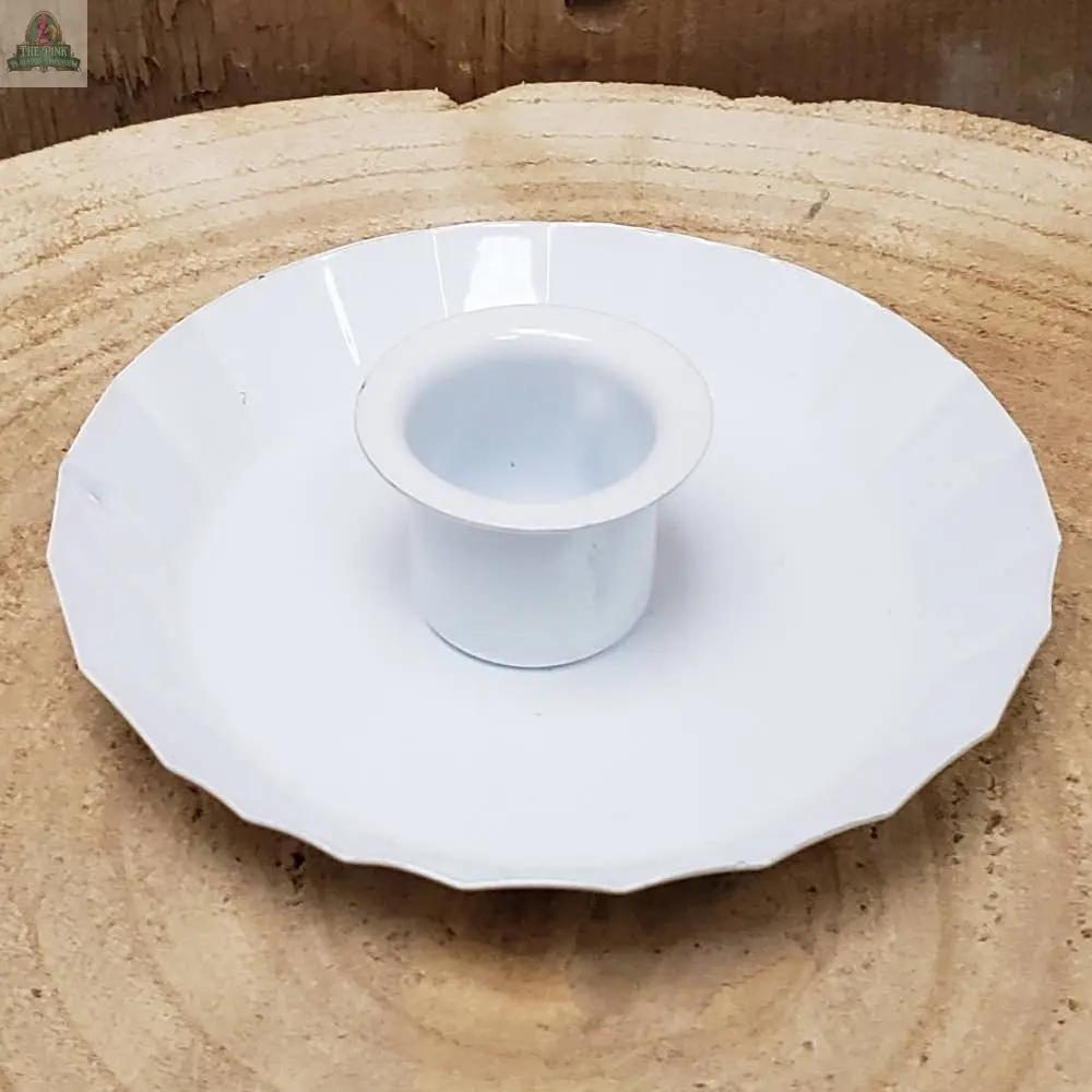 A black ceramic Fluted Edge Taper Holder sits at the center of a matching saucer with a fluted edge, placed on a light wooden surface.