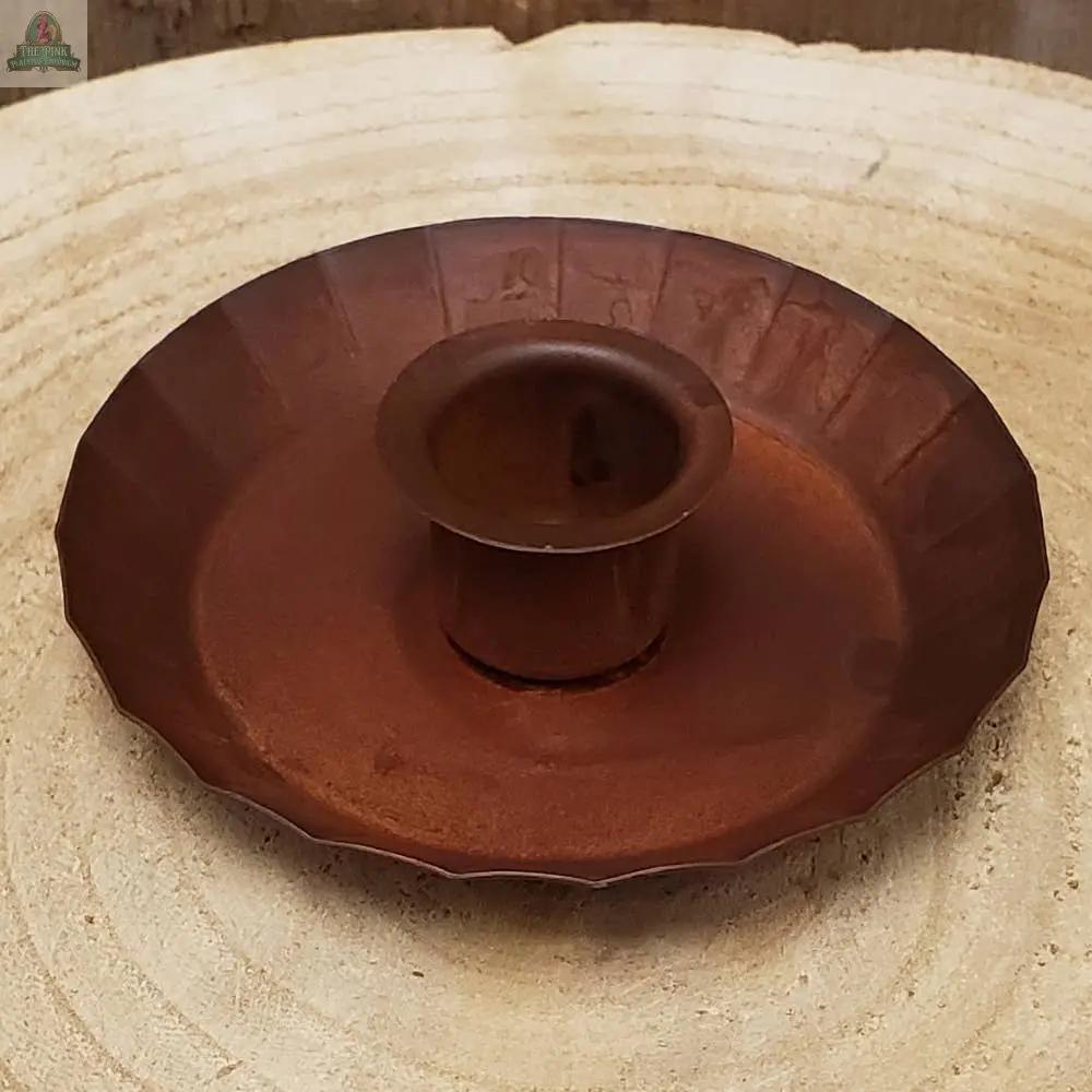 The Fluted Edge Taper Holder: Rust features a rustic brown metal design with a round base and gently fluted edge, perfect for showcasing your favorite taper candle on any surface.