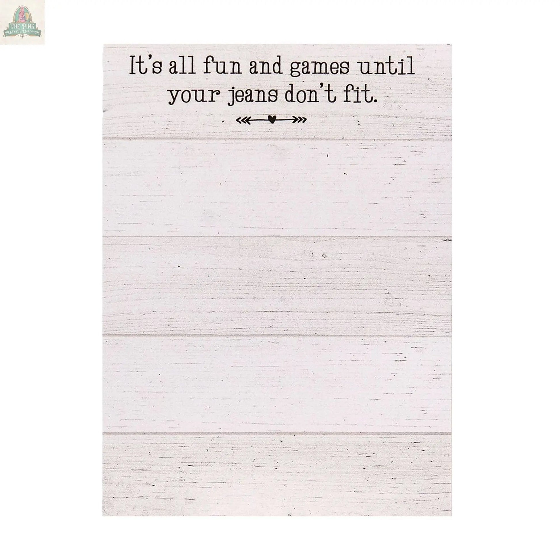 The Fun and Games Mini Notepad features a magnetic back, white wooden background, the phrase “It’s all fun and games until your jeans don’t fit,” decorative arrows, and is made in the USA.