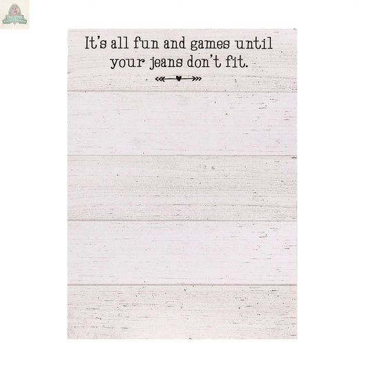 The Fun and Games Mini Notepad features a magnetic back, white wooden background, the phrase “It’s all fun and games until your jeans don’t fit,” decorative arrows, and is made in the USA.